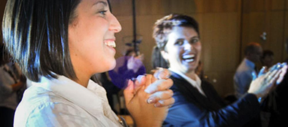 Two women clapping and laughing during a warm up