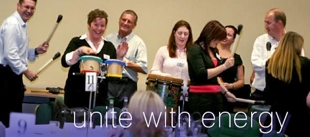 Happy people playing a variety of instruments in a percussion workshop team building activity